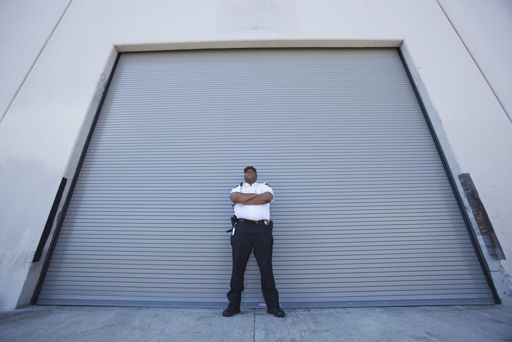 male security guard in front of large shutter entrace