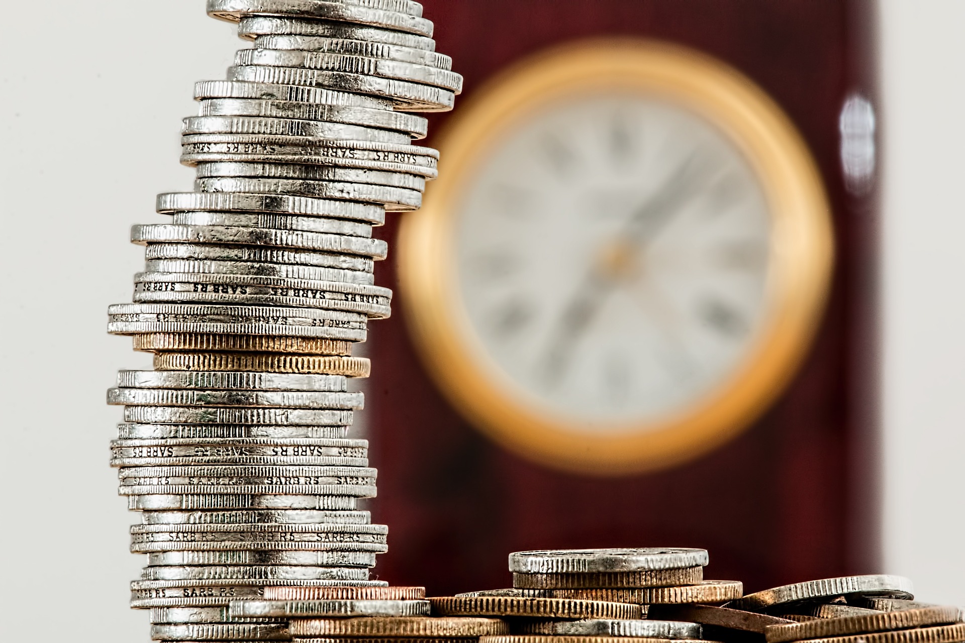 stack of coins with clock in the background