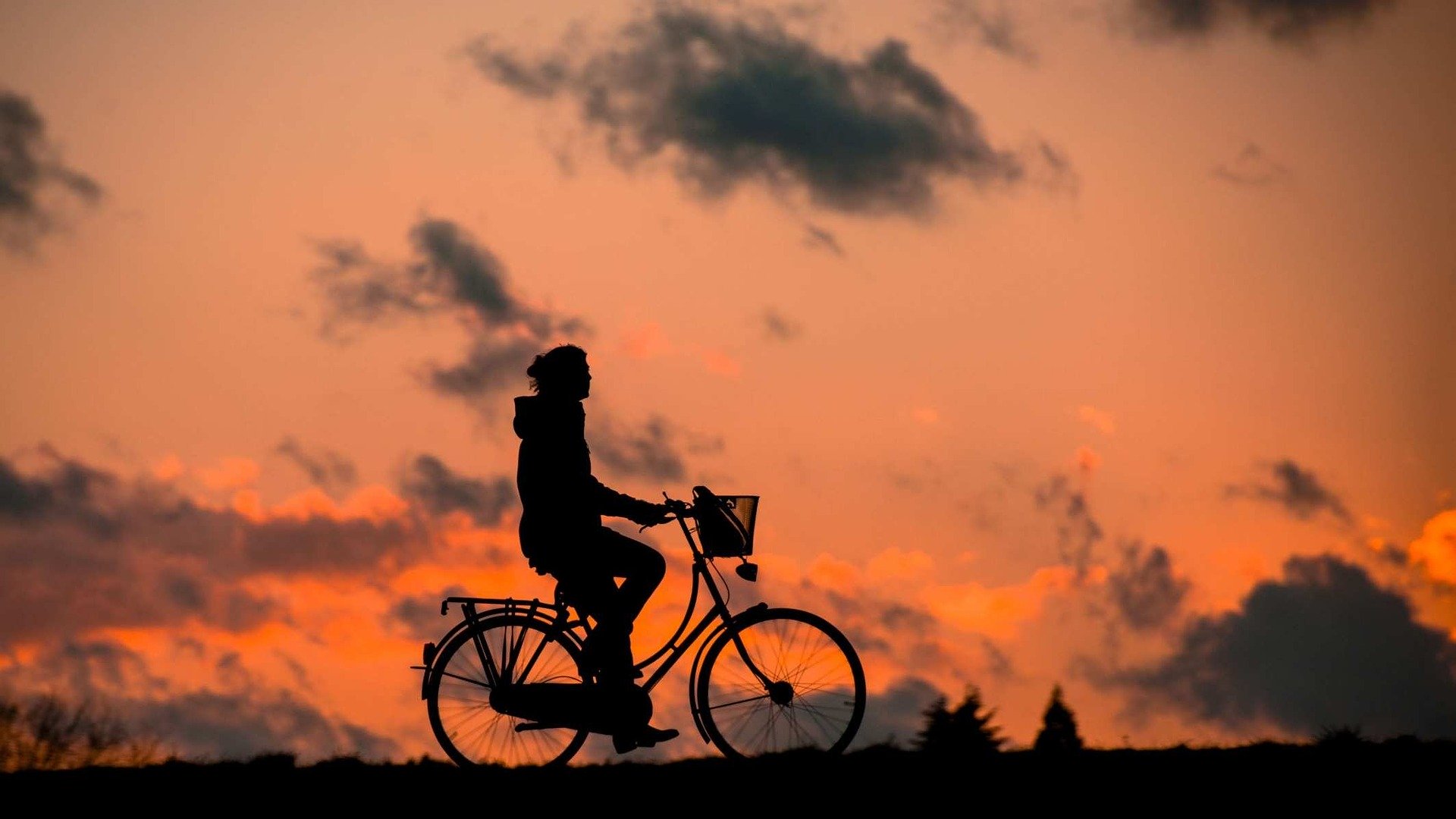 silhouette of a person on a bike at sunset