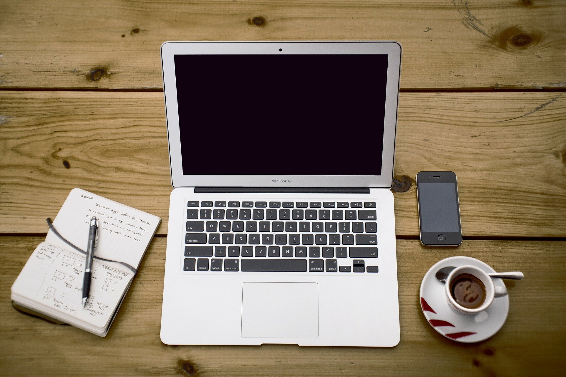 desk setup with laptop, phone, and note pad