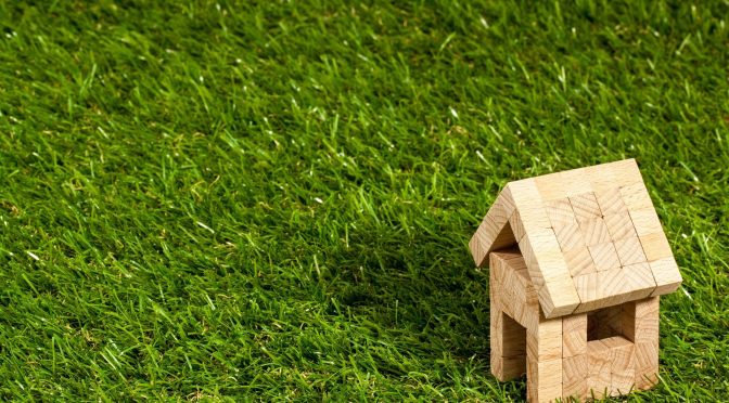 abstract image of small toy house on a green lawn