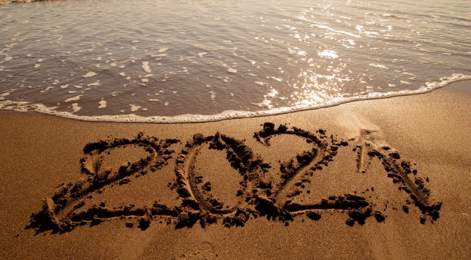 2021 written in the sand next to the water on a beach